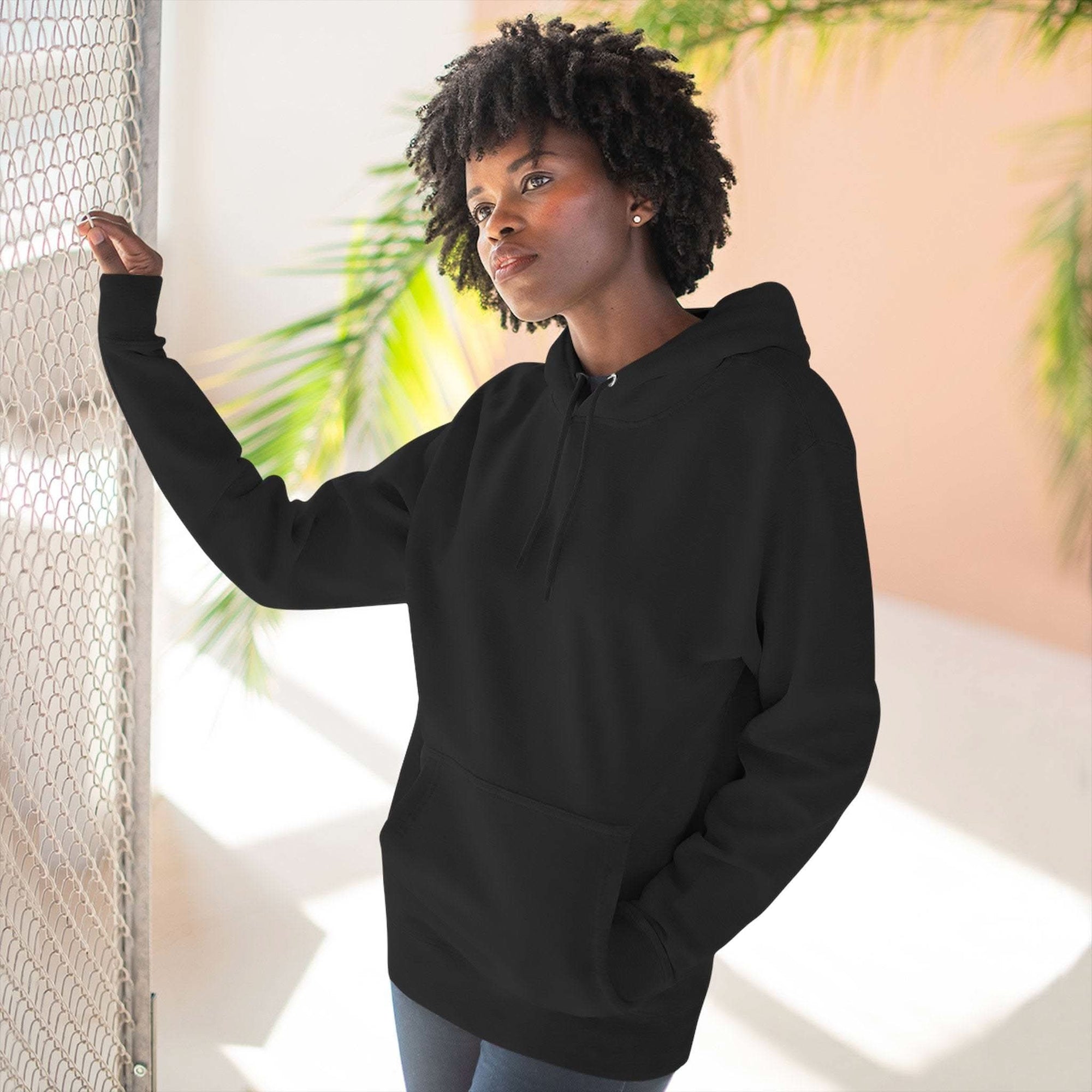 Black fleece hoodie with adjustable hood and kangaroo pocket worn by woman indoors