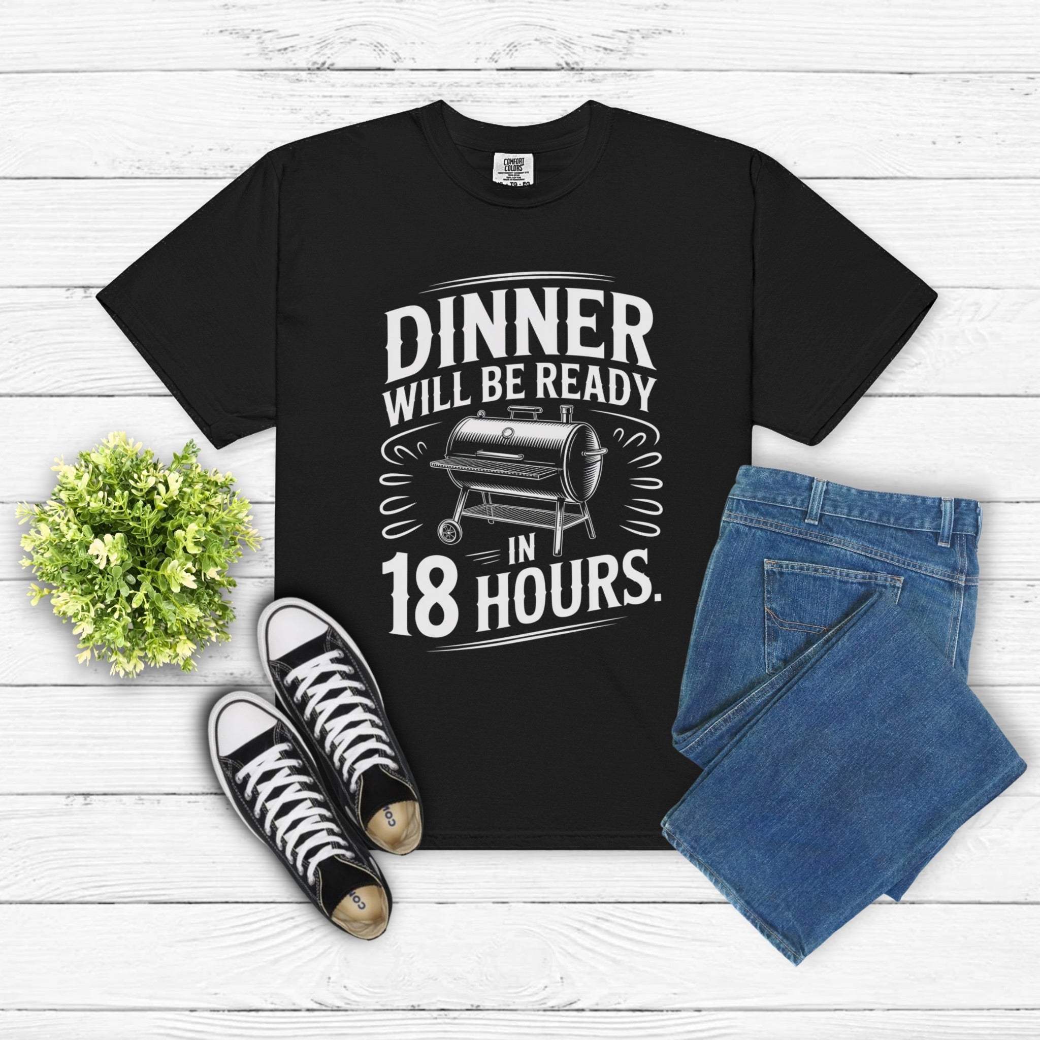 Black "Dinner Will Be Ready in 18 Hours" meat smoker graphic t-shirt with jeans and sneakers on white wooden background