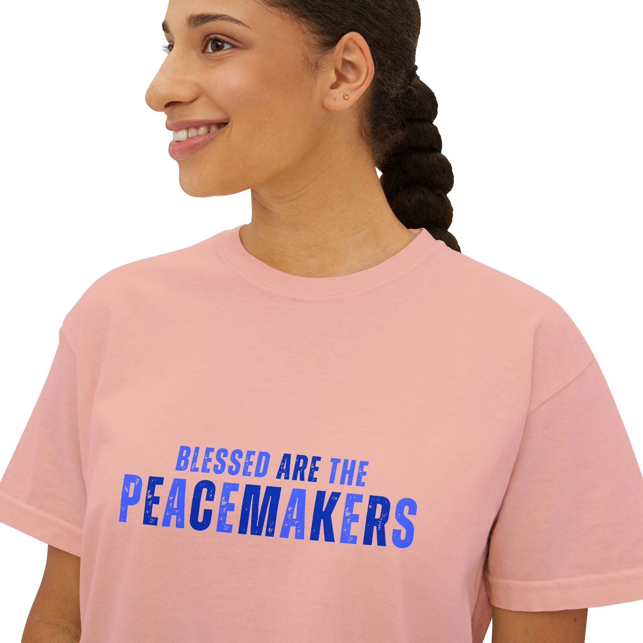 Women wearing pink boxy Tee Blessed be the Peacemakers with blue text promoting peace and harmony