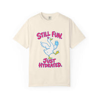 A cream-colored short-sleeve t-shirt with a graphic of a white goose holding a blue water bottle, with the text 'STILL FUN. JUST HYDRATED.