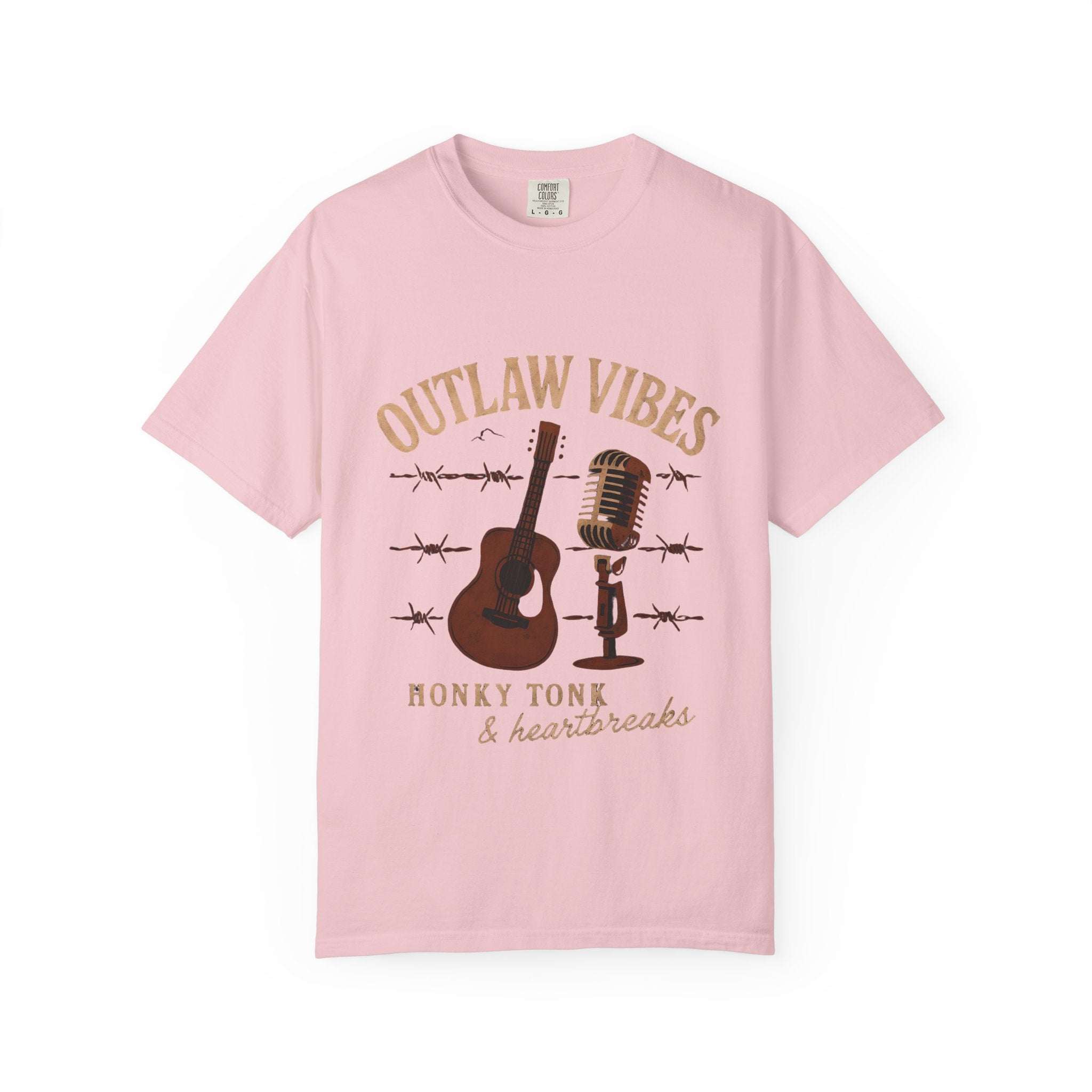 Pink t-shirt with 'Outlaw Vibes' graphic design featuring a guitar, microphone, and barbed wire on a white background.