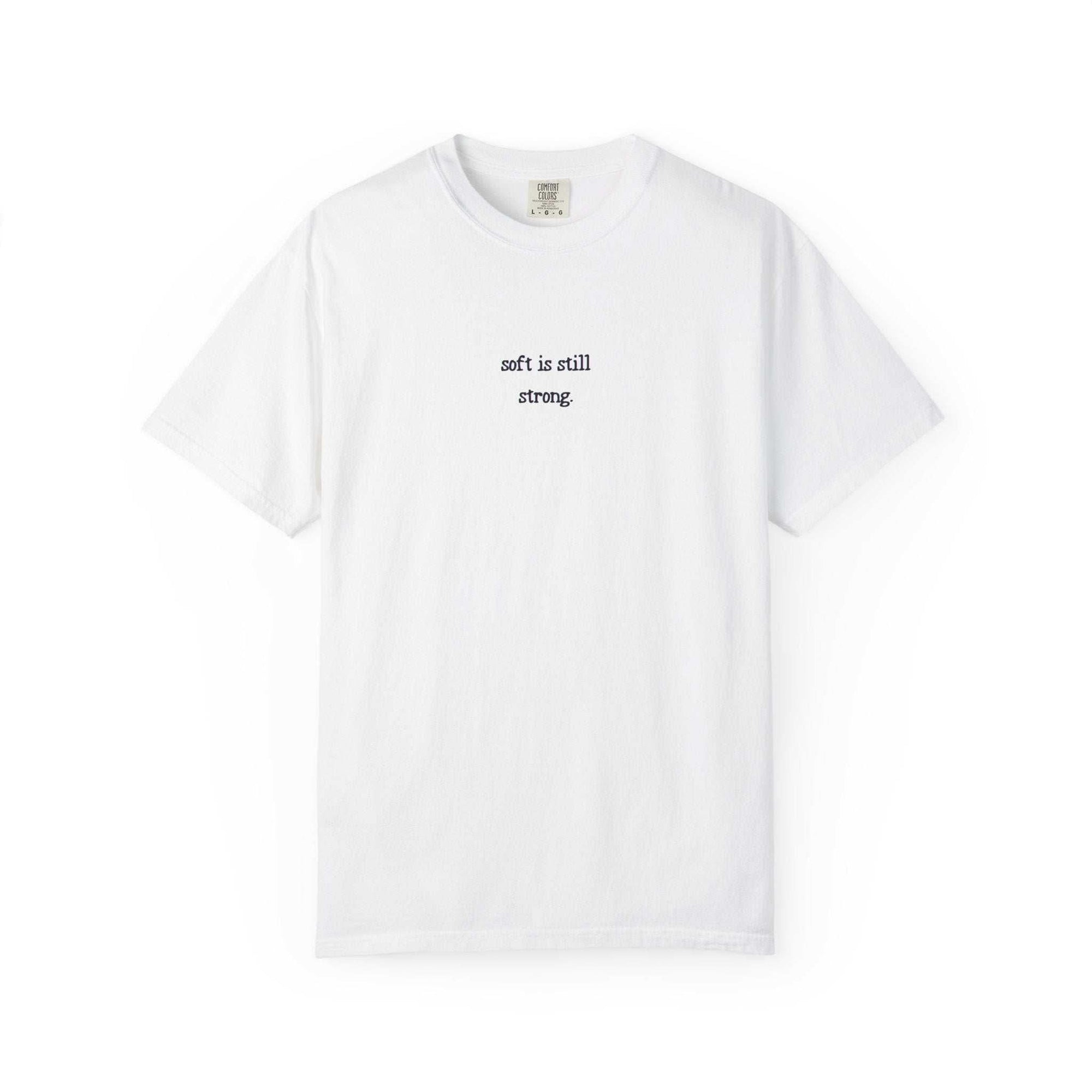 White t-shirt with text 'soft is still strong' on a white background