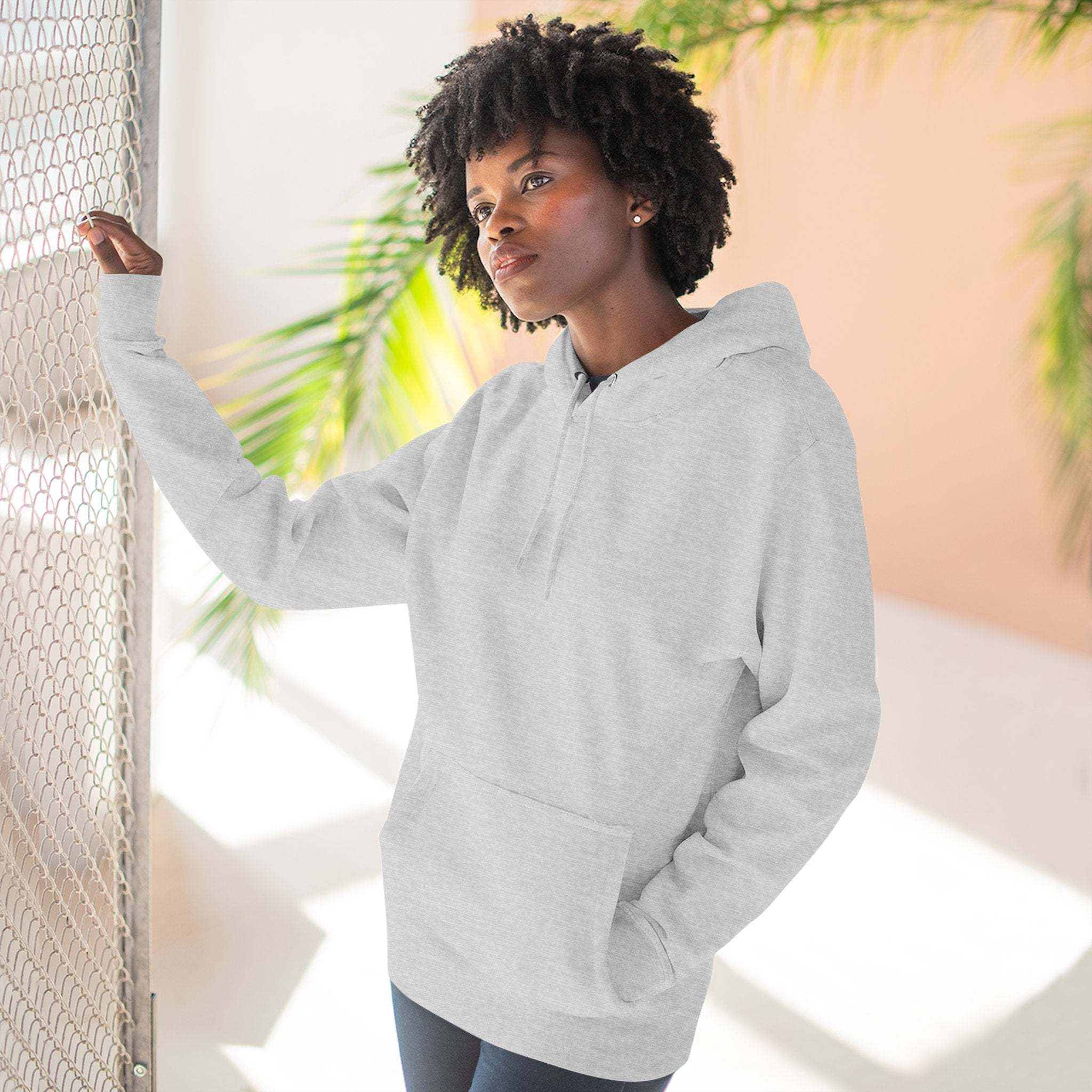 Woman wearing cozy light gray fleece hoodie with kangaroo pocket and adjustable hood indoors