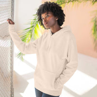 Woman wearing a cozy beige fleece hoodie with kangaroo pocket standing by a window