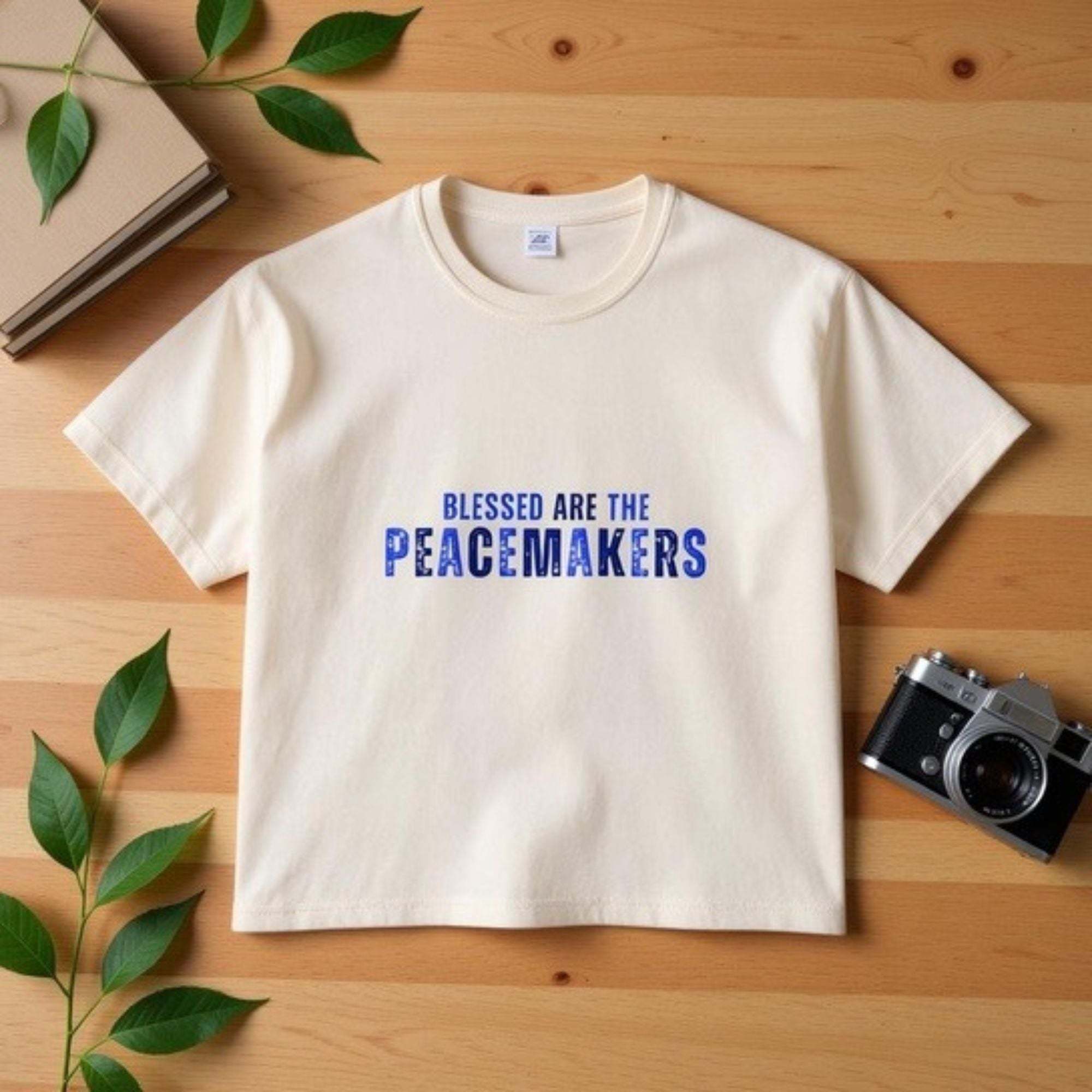 Women's boxy tee in vintage cream with "Blessed are the Peacemakers" blue text, 100% cotton, casual positive message shirt