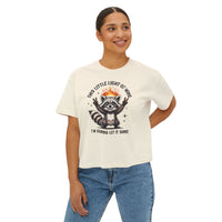 Person wearing a white t-shirt with a graphic design of a raccoon and text.