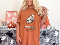 Model wearing a yam orange mahjong T-shirt with a ghost holding a joker tile above a tile rack and “ghosted (he took the joker)” lettering.