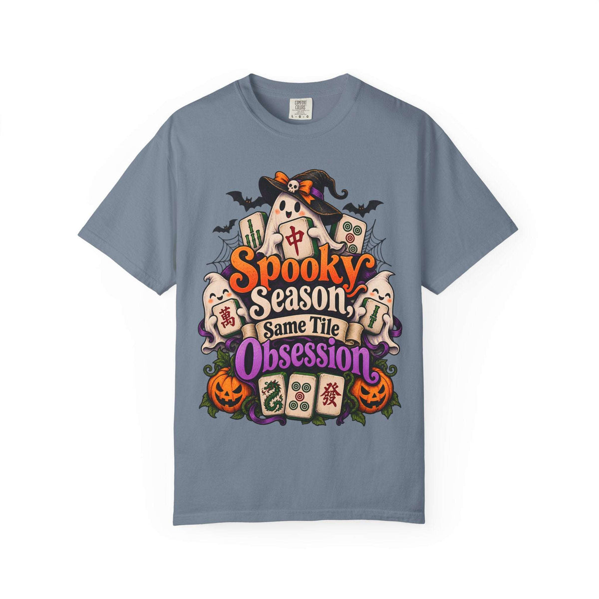 Flat lay of a blue jean Halloween mahjong T-shirt with ghosts, pumpkins, mahjong tiles and “Spooky Season, Same Tile Obsession” lettering.
