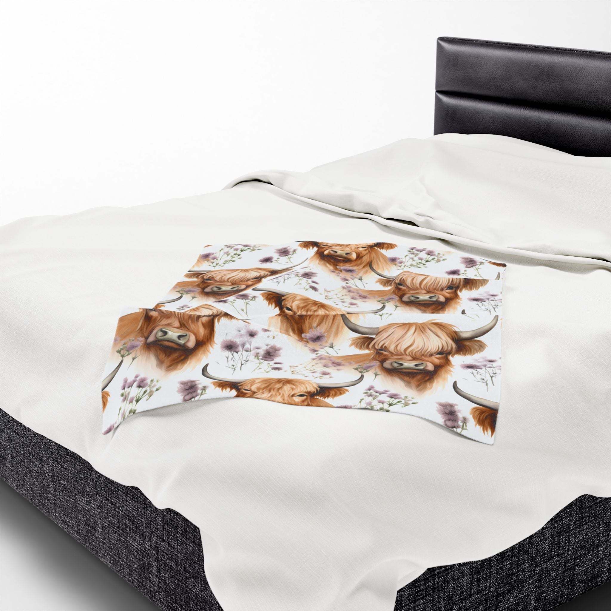 Plush blanket with floral highland cow design on bed, cozy and rustic velveteen fabric