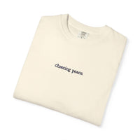 Folded cream-colored t-shirt with 'choosing peace' text on a white background