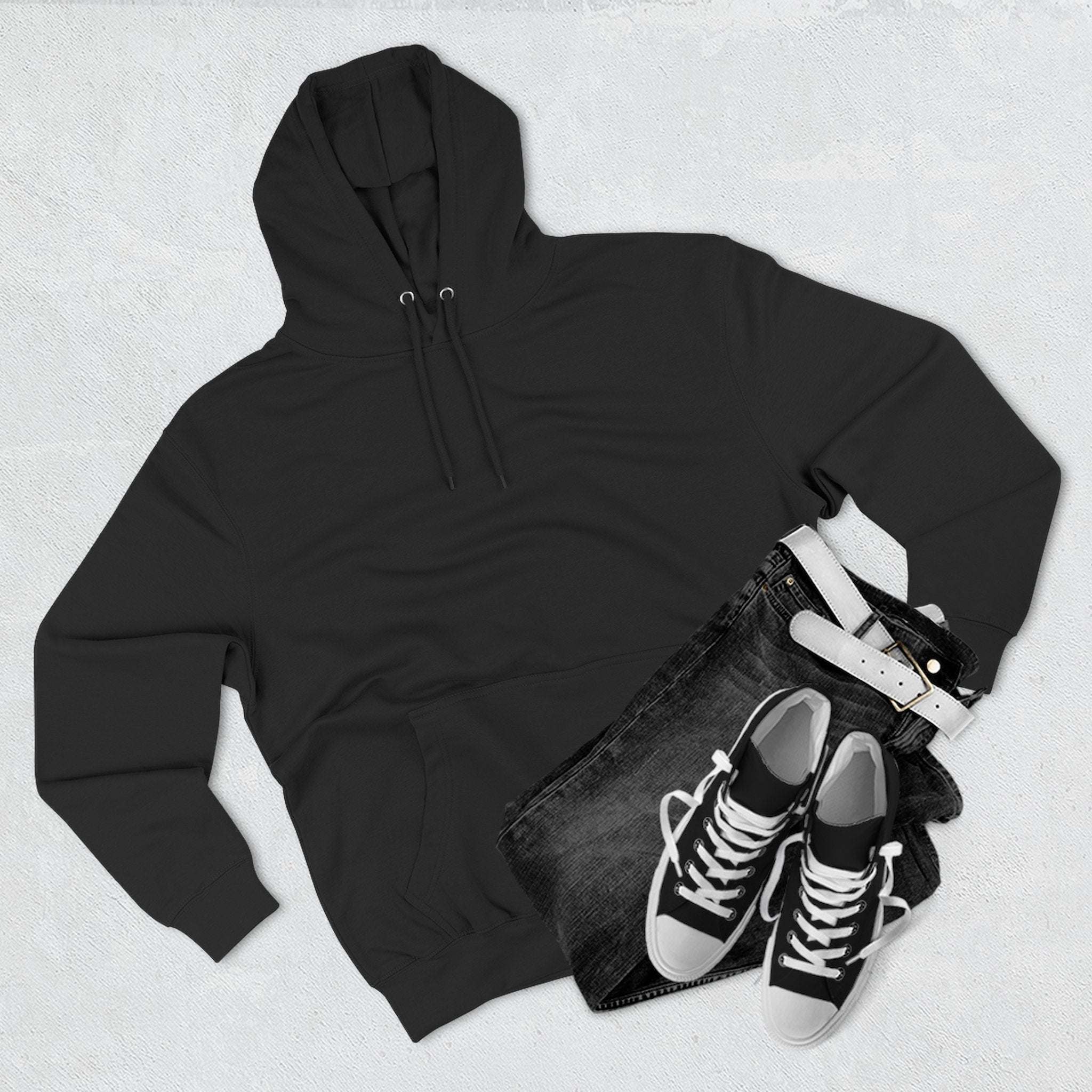 Black fleece hoodie with kangaroo pocket paired with black jeans and sneakers on gray background