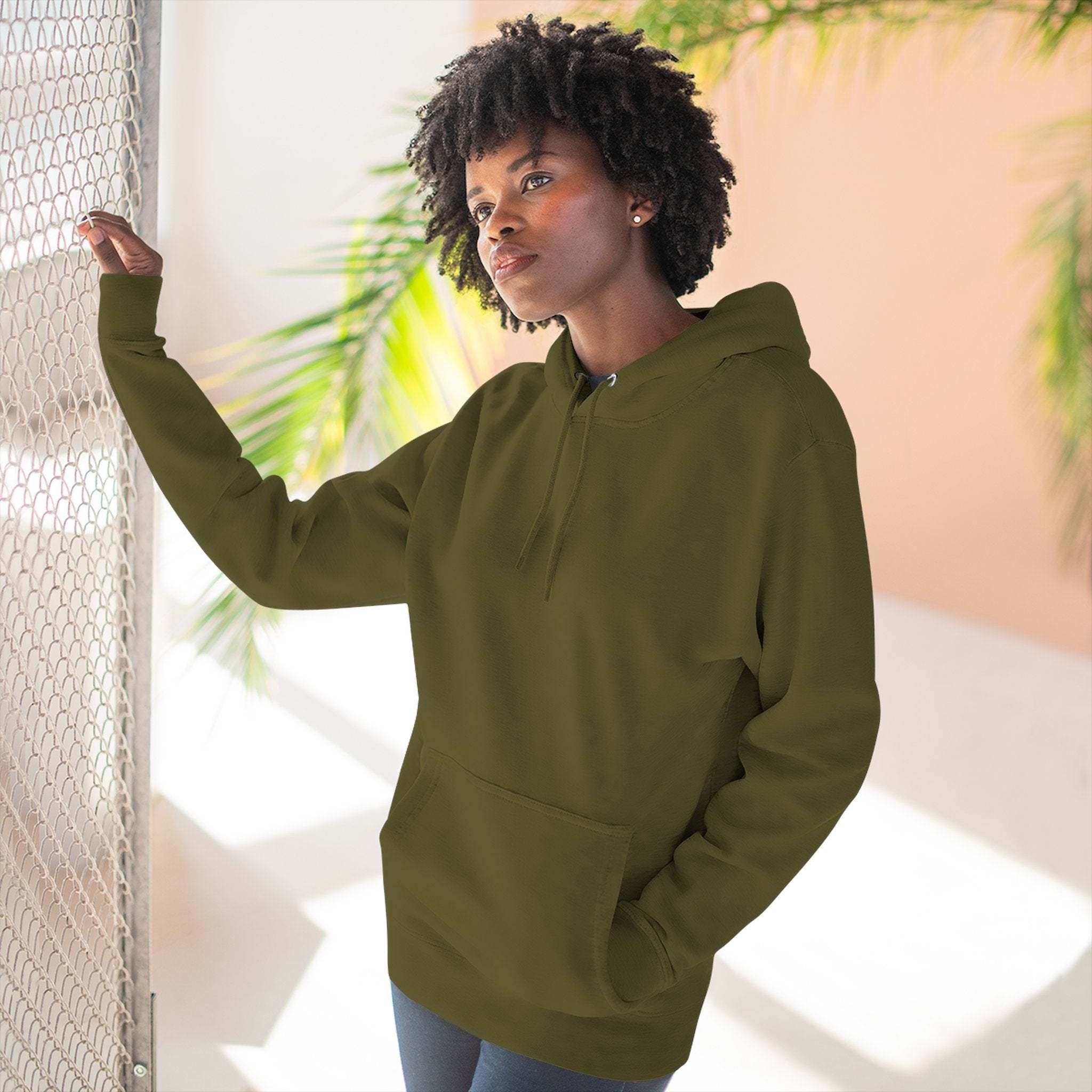 Woman wearing olive green fleece hoodie with kangaroo pocket and adjustable hood indoors