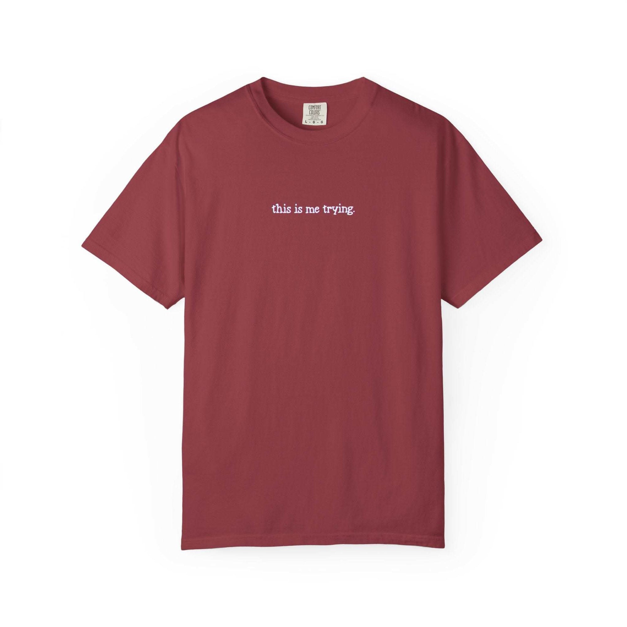 Maroon t-shirt with 'this is me trying' text on a white background