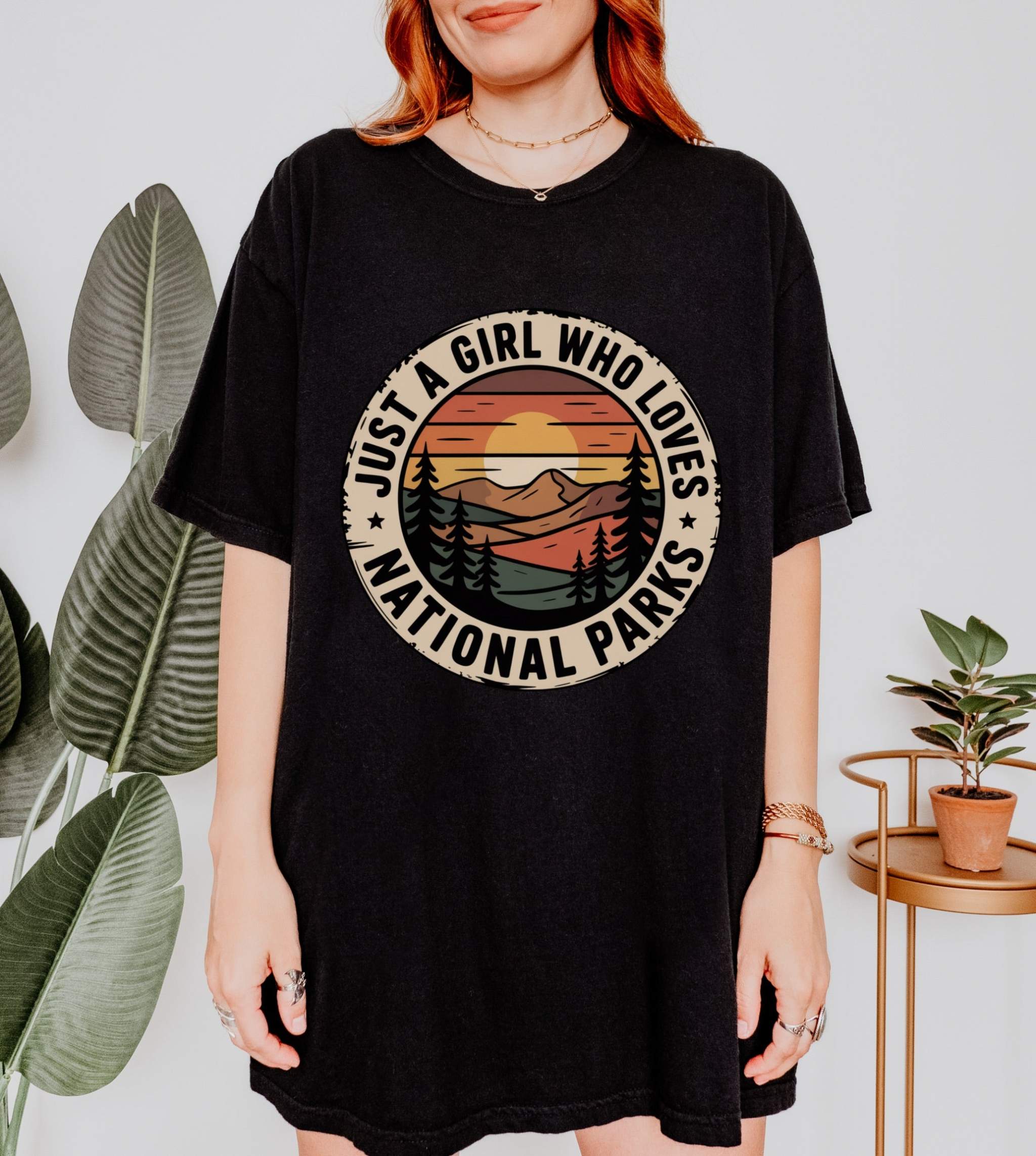 Woman wearing black National Parks T-Shirt with mountain sunset graphic and "Just a Girl Who Loves National Parks" text