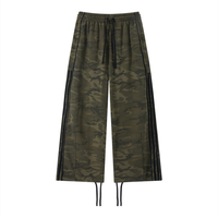 Unisex camo wide leg sweatpants with olive camouflage, black side webbing, elastic waistband, and adjustable cuffs for streetwear style