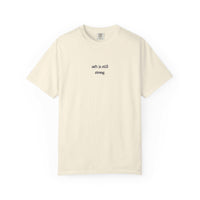 Beige t-shirt with text 'soft is still strong' on a white background