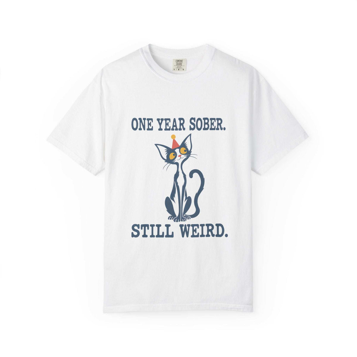 Flat lay of an white Comfort Colors 1717 t-shirt featuring a navy cat in a red party hat and “One Year Sober. Still Weird.” lettering.