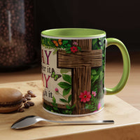 Mug with floral design and text on a wooden surface with coffee beans and a spoon.