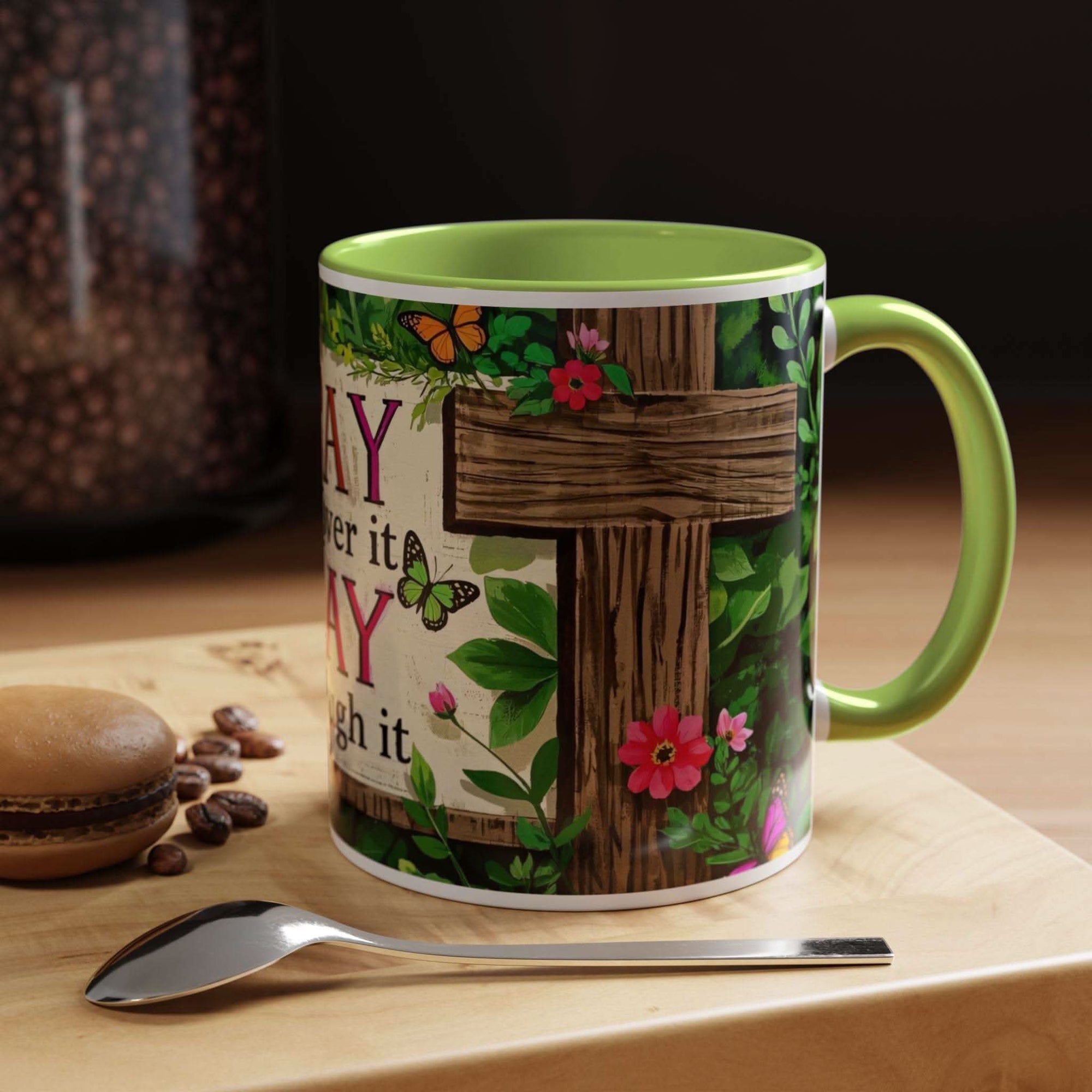 Mug with floral design and text on a wooden surface with coffee beans and a spoon.