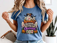 Model wearing a blue jean Halloween mahjong T-shirt with ghosts, pumpkins, mahjong tiles and “Spooky Season, Same Tile Obsession” lettering.
