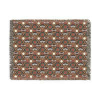 Victorian Gothmas Woven Blanket with candlelight colors and colorful fringed edges draped on a dark velvet bed