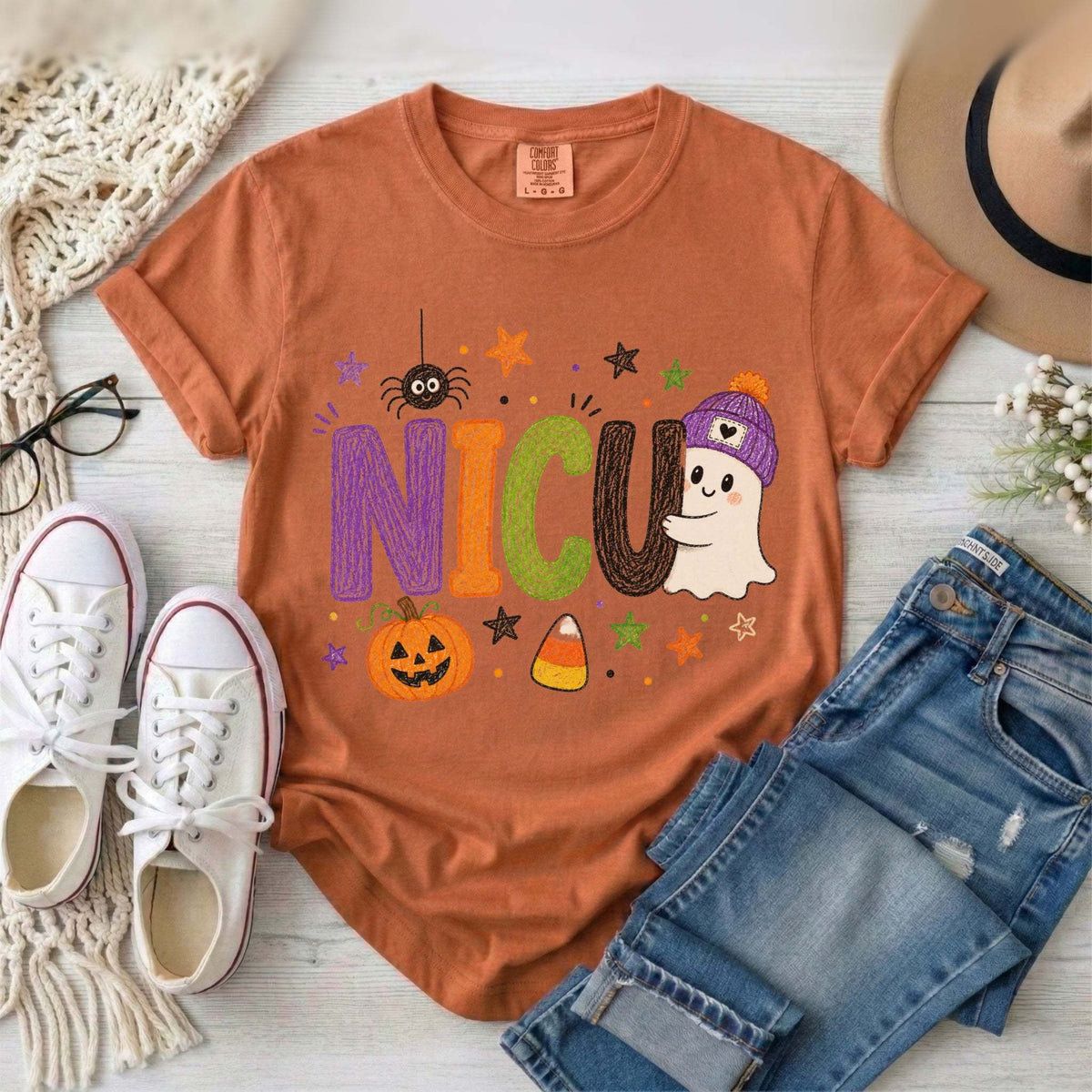Yam orange NICU nurse Halloween T-shirt with colorful crayon-style lettering, a smiling ghost in a purple beanie, pumpkin, and candy corn.