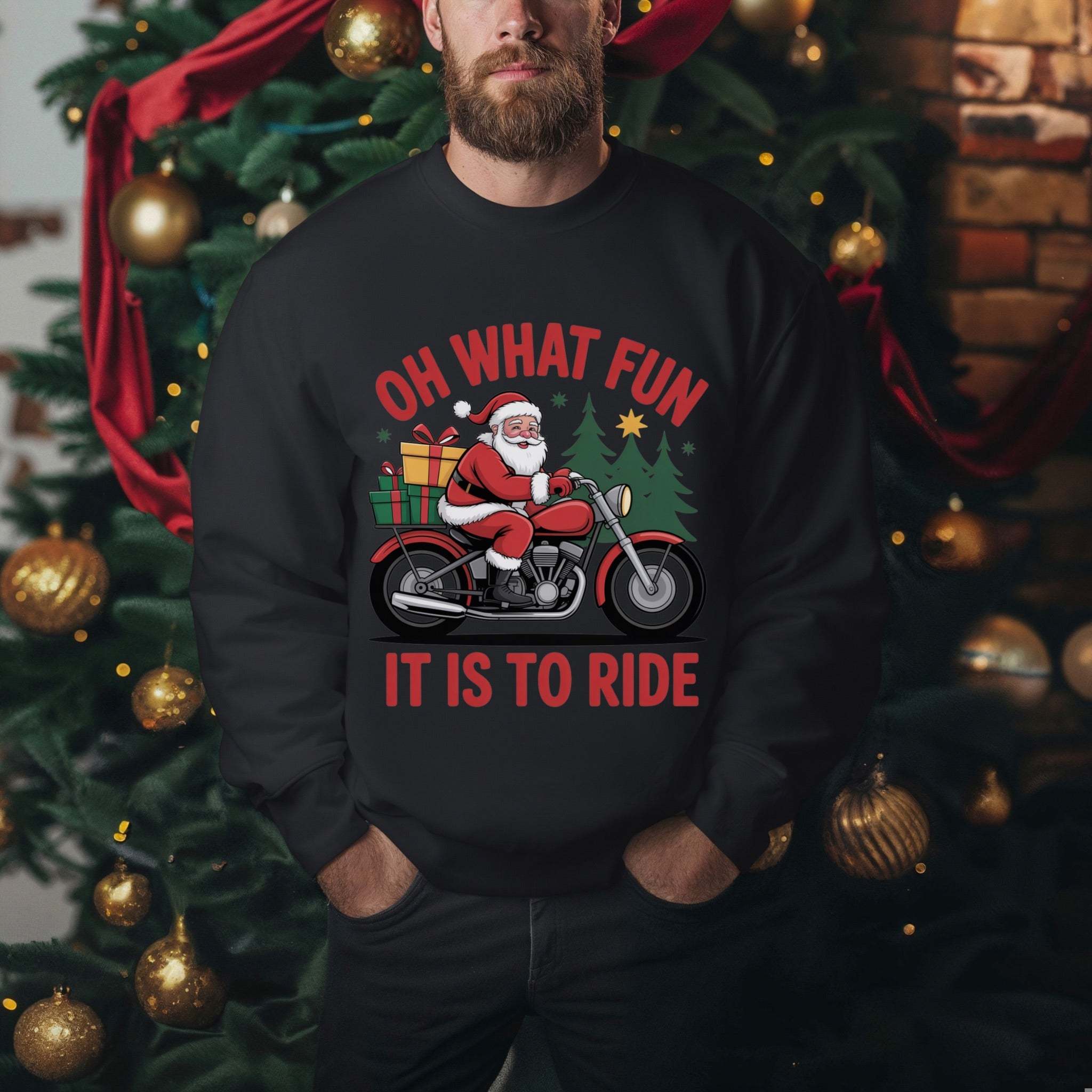 Man wearing black Motorcycle Santa Sweatshirt with Santa on motorcycle and holiday gifts design in front of Christmas tree