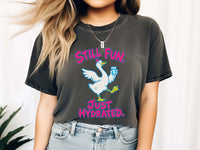 Female model wearing pepper grey Comfort Colors crewneck t-shirt featuring a graphic of a white goose holding a blue water bottle, with the pink text 'STILL FUN. JUST HYDRATED.