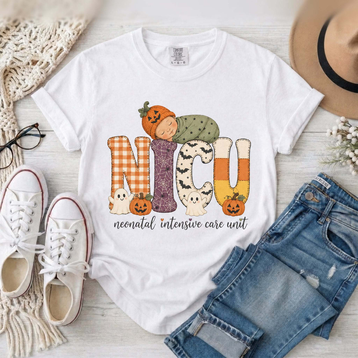 White NICU nurse Halloween T-shirt with patchwork lettering, a sleeping baby in a pumpkin hat, ghosts, and jack-o’-lanterns.