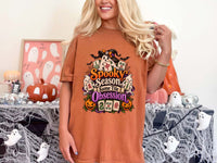 Model wearing a yam orange Halloween mahjong T-shirt with ghosts, pumpkins, mahjong tiles and “Spooky Season, Same Tile Obsession” lettering.