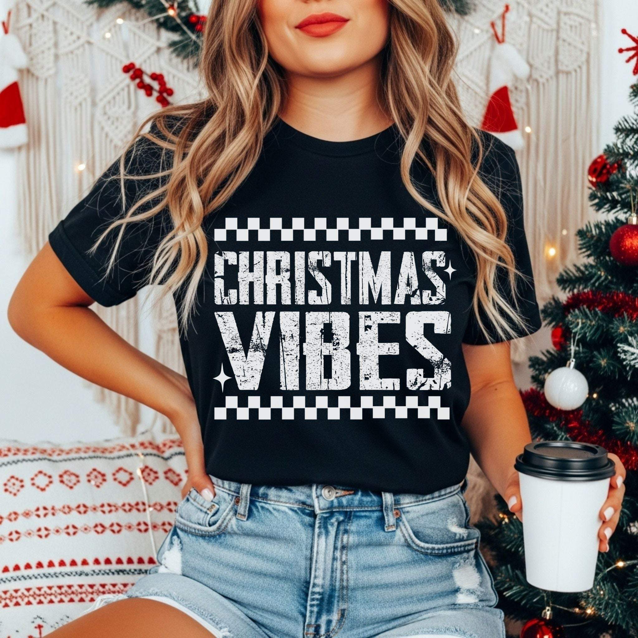 Woman wearing distressed Christmas Vibes black garment-dyed t-shirt with festive holiday decor background