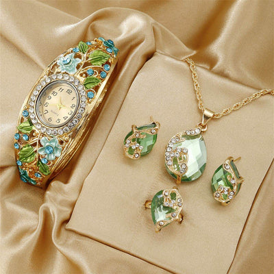 Blue vintage court style women's wrist watch with gold-tone floral design and matching green gemstone jewelry set on satin background