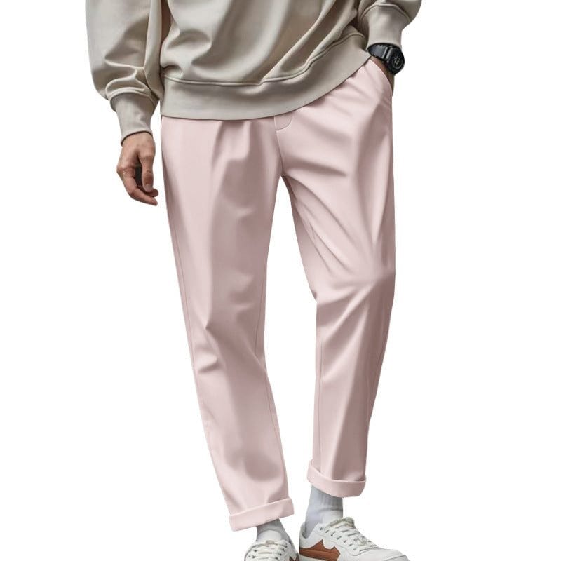 Men's casual loose fit pink trousers with pockets and drawstring waist, styled with rolled cuffs and paired with white sneakers and a beige sweatshirt.