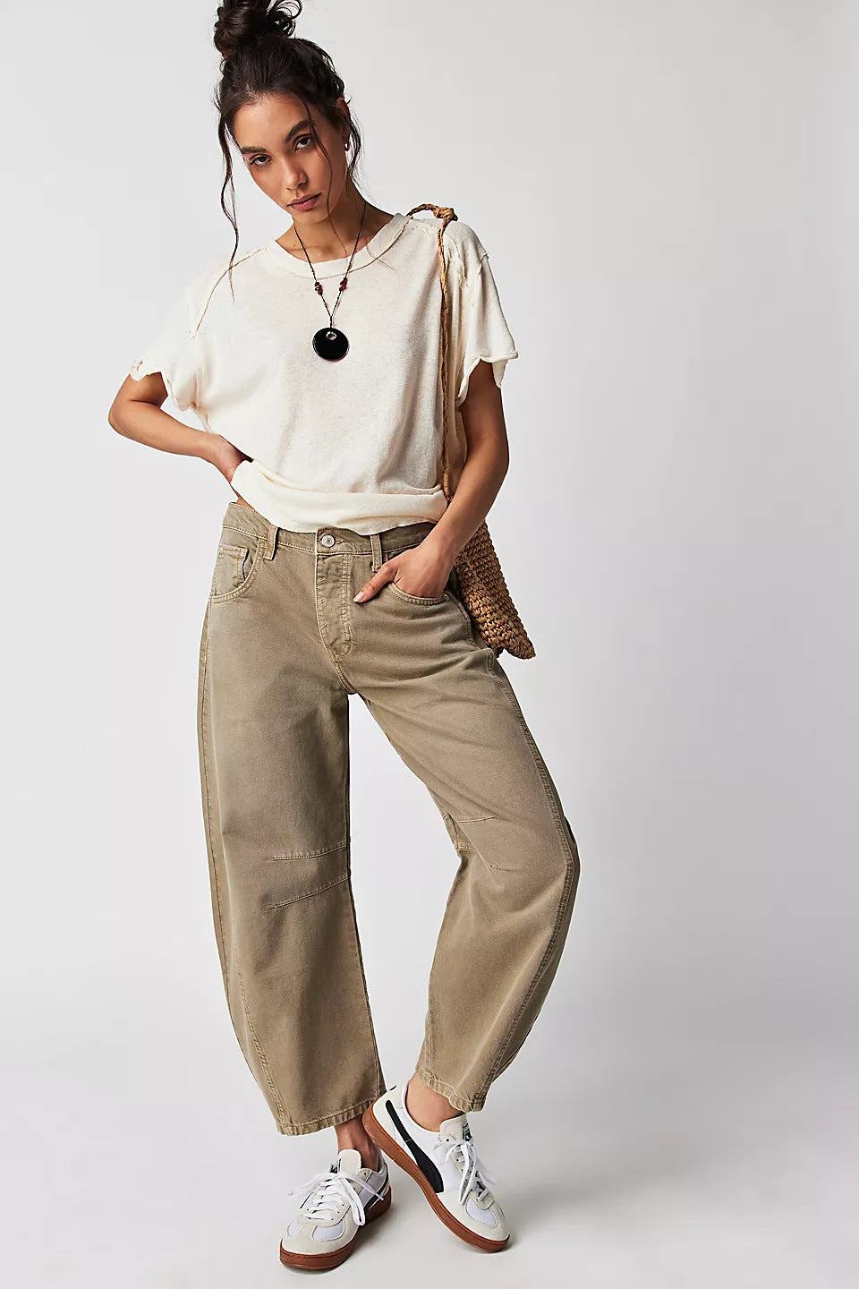 Woman wearing high stretch mid-rise wide leg loose fit denim jeans in dark khaki with casual white t-shirt and sneakers