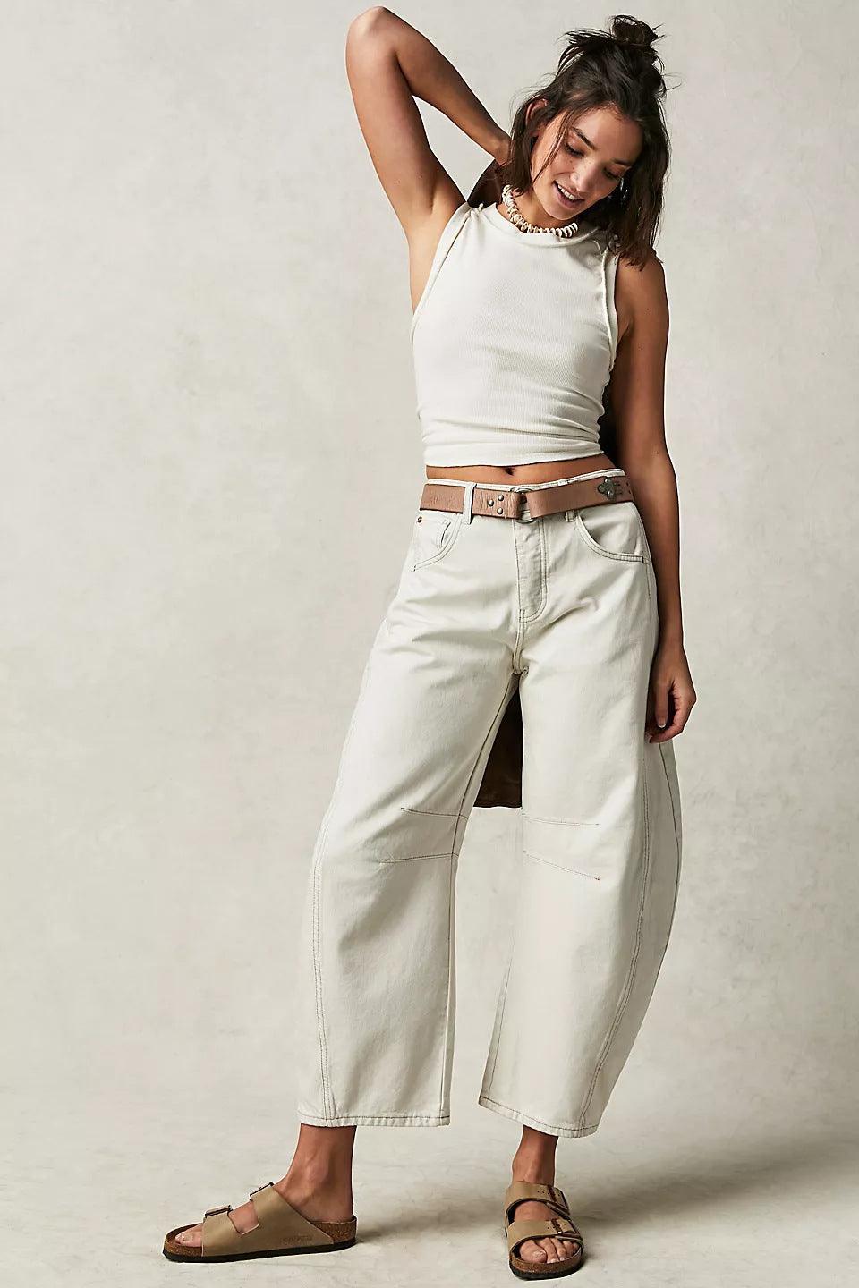 Woman wearing high stretch mid-rise white wide-leg denim jeans with casual sleeveless top and sandals