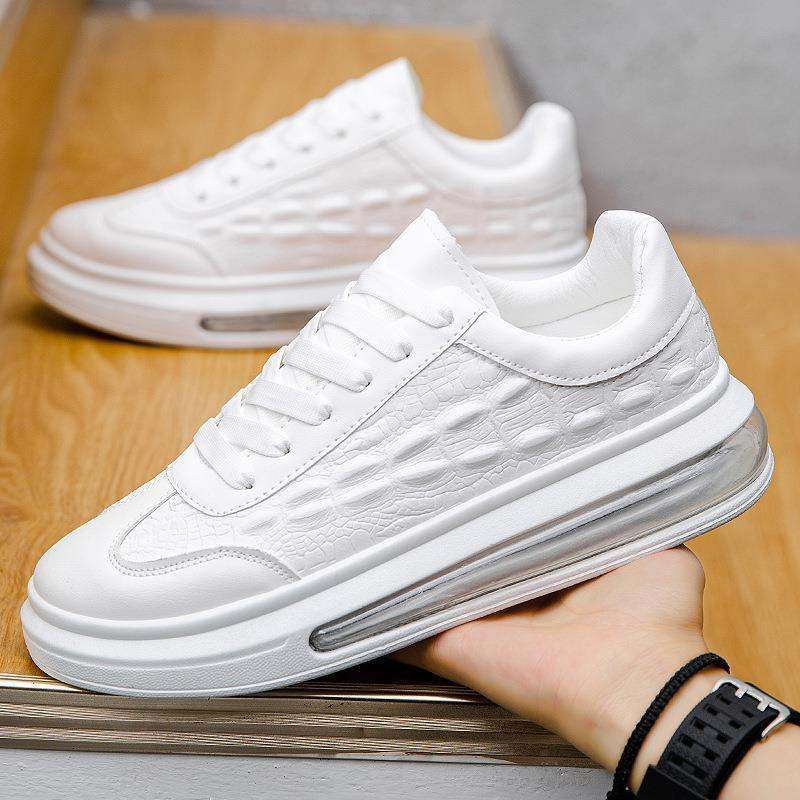 White trendy leather men's casual sneakers with thick rubber sole and textured design on wooden surface