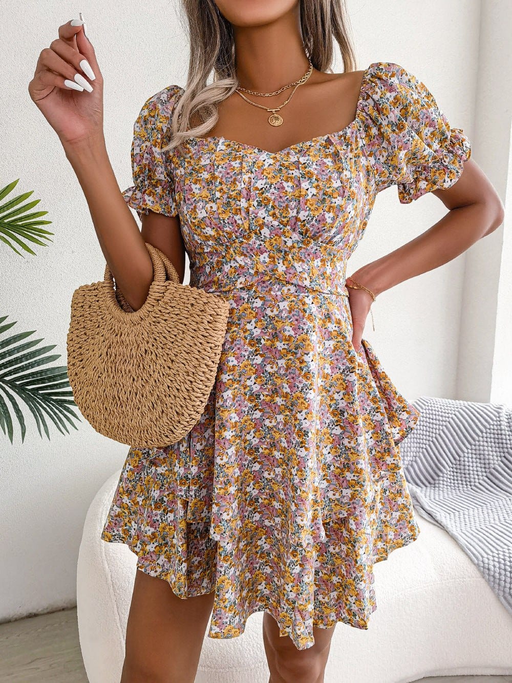 Women mini dress with floral print, puff short sleeves, high waist, and loose swing hem, styled with a woven handbag.