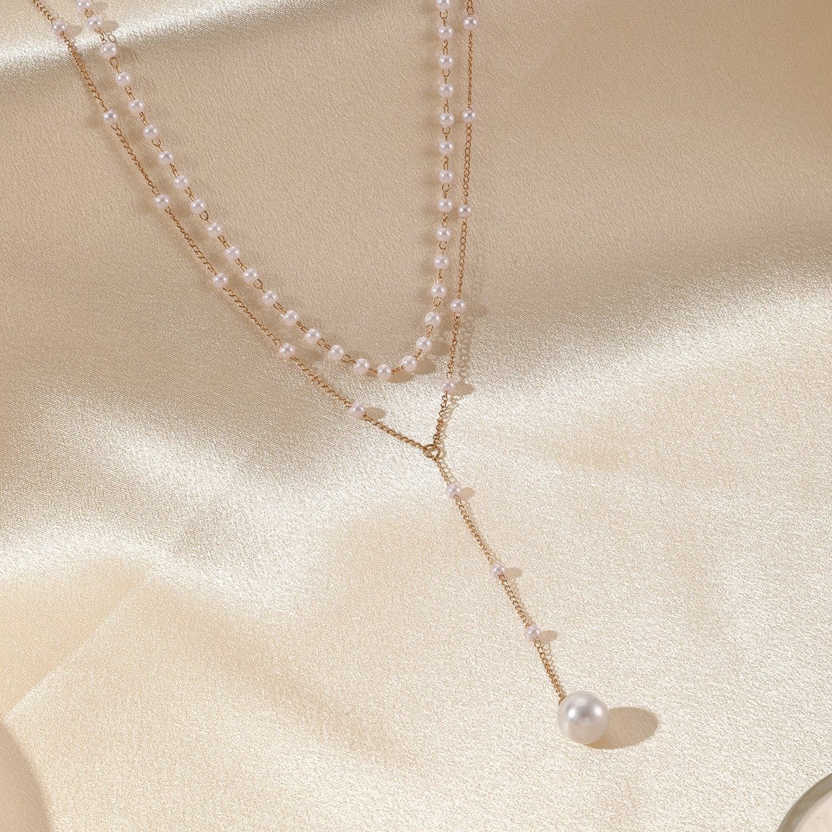 Elegant pearl double layer twin necklace with gold alloy chain and geometric design on satin background