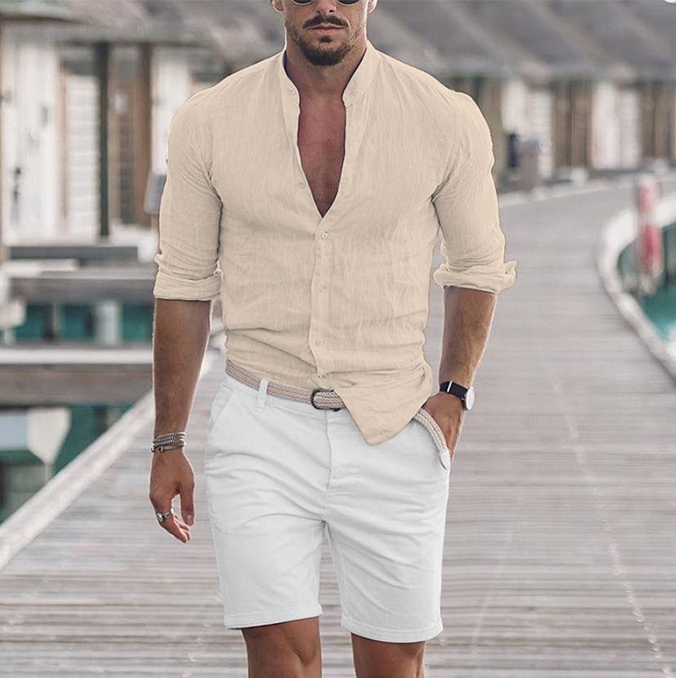 Man wearing beige men's long sleeve casual button shirt paired with white shorts on wooden dock in outdoor setting