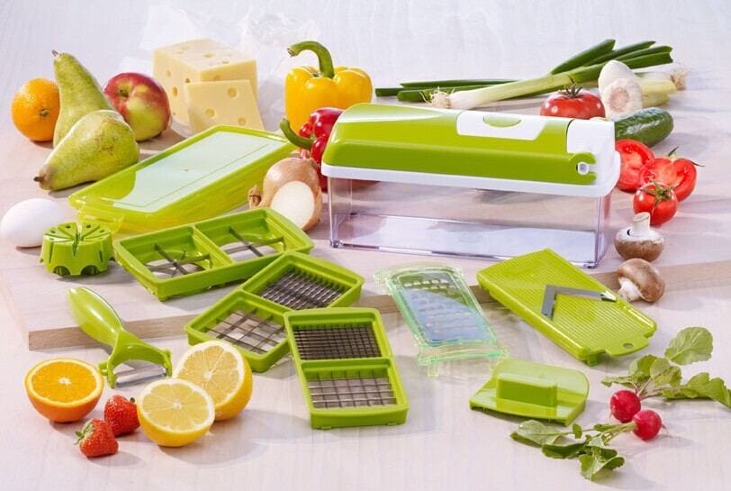 12pcs green food chopper with multiple stainless steel blades and accessories for slicing, dicing, and grating vegetables and fruits on a kitchen counter with fresh produce and cheese.