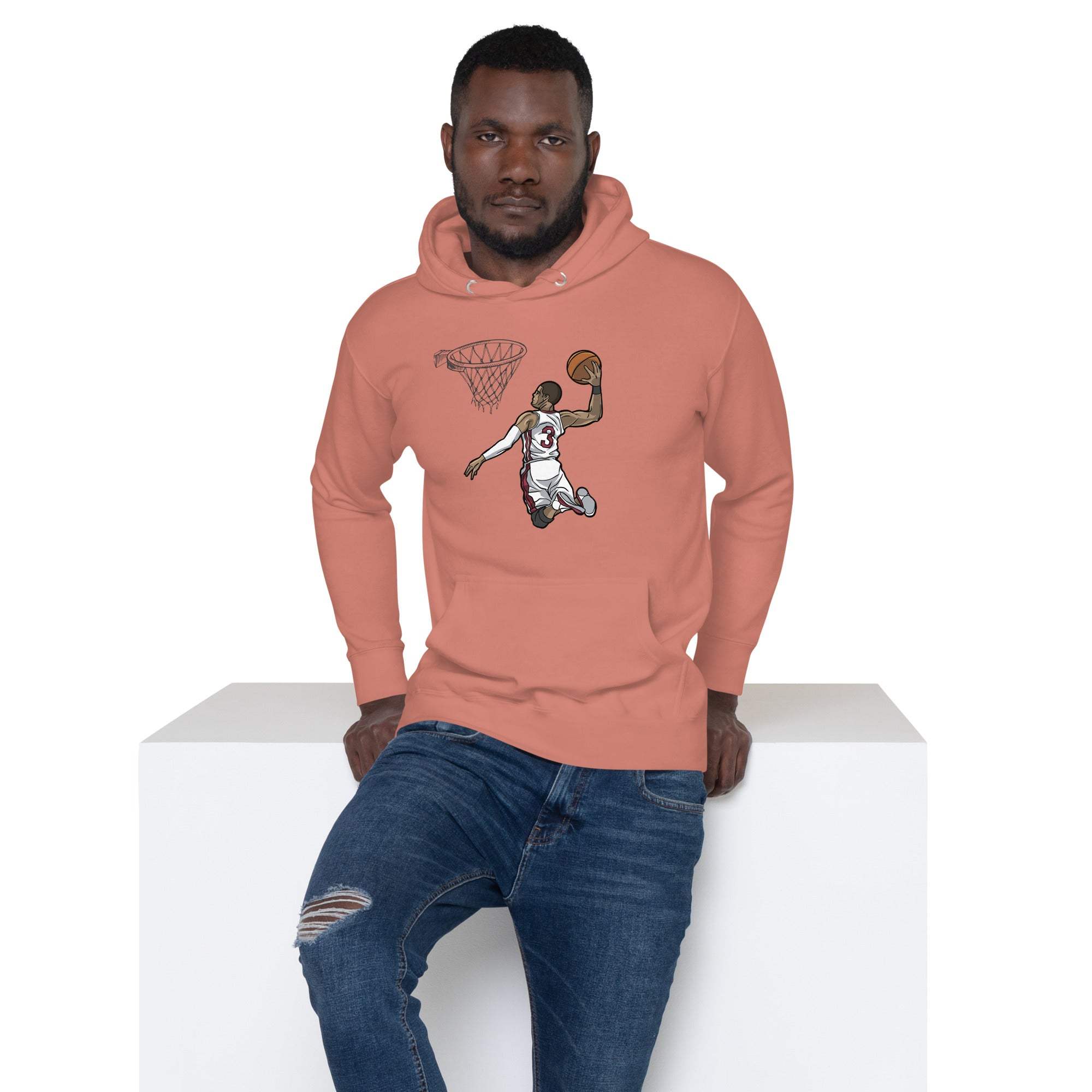 Man wearing a pink Basketball Dunk Hoodie with slam dunk graphic and blue jeans seated on white block