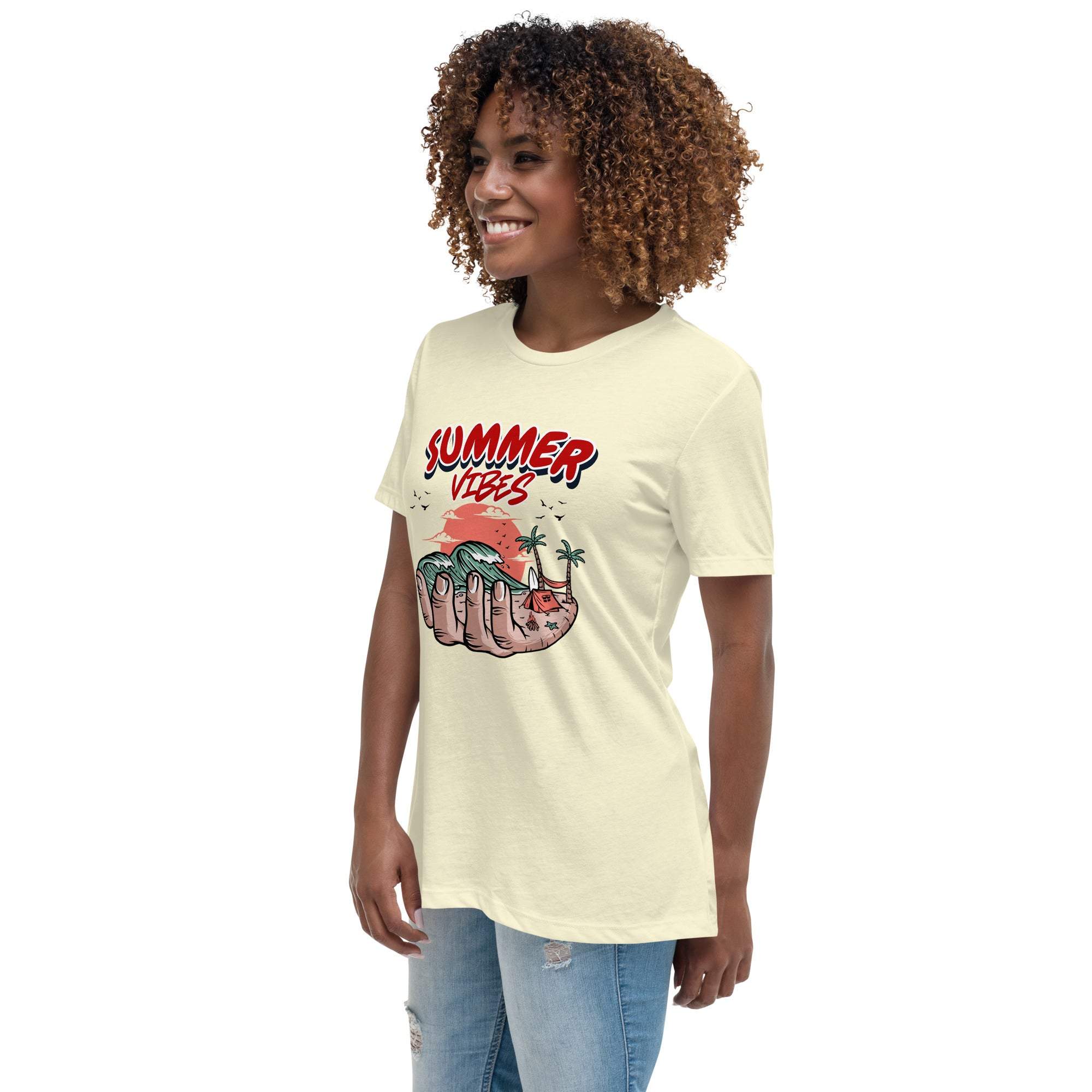 Woman wearing a light-colored Summer Vibes T-Shirt featuring a retro beach scene graphic in a hand, paired with jeans.