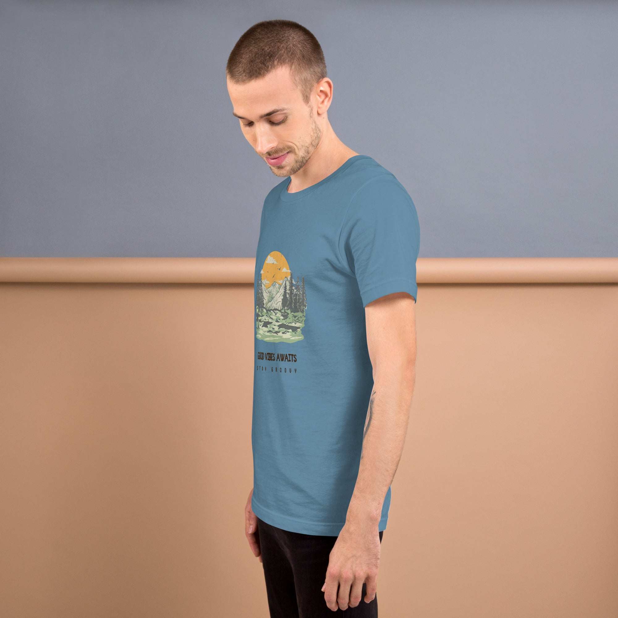 Man wearing a soft, lightweight blue Good Vibes Awaits T-shirt with mountain graphic on front