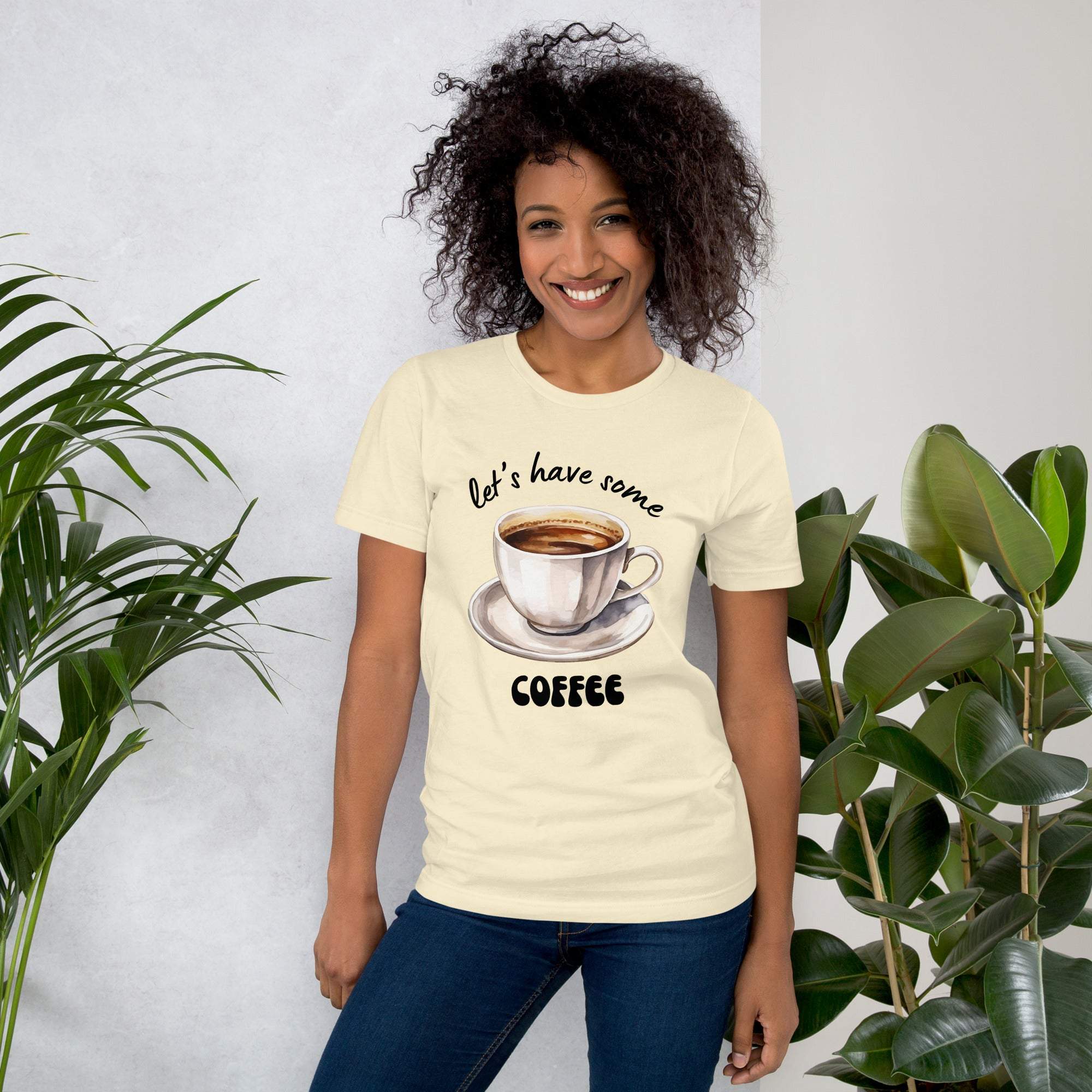 Woman wearing cream coffee t-shirt with "let's have some coffee" text and coffee cup graphic