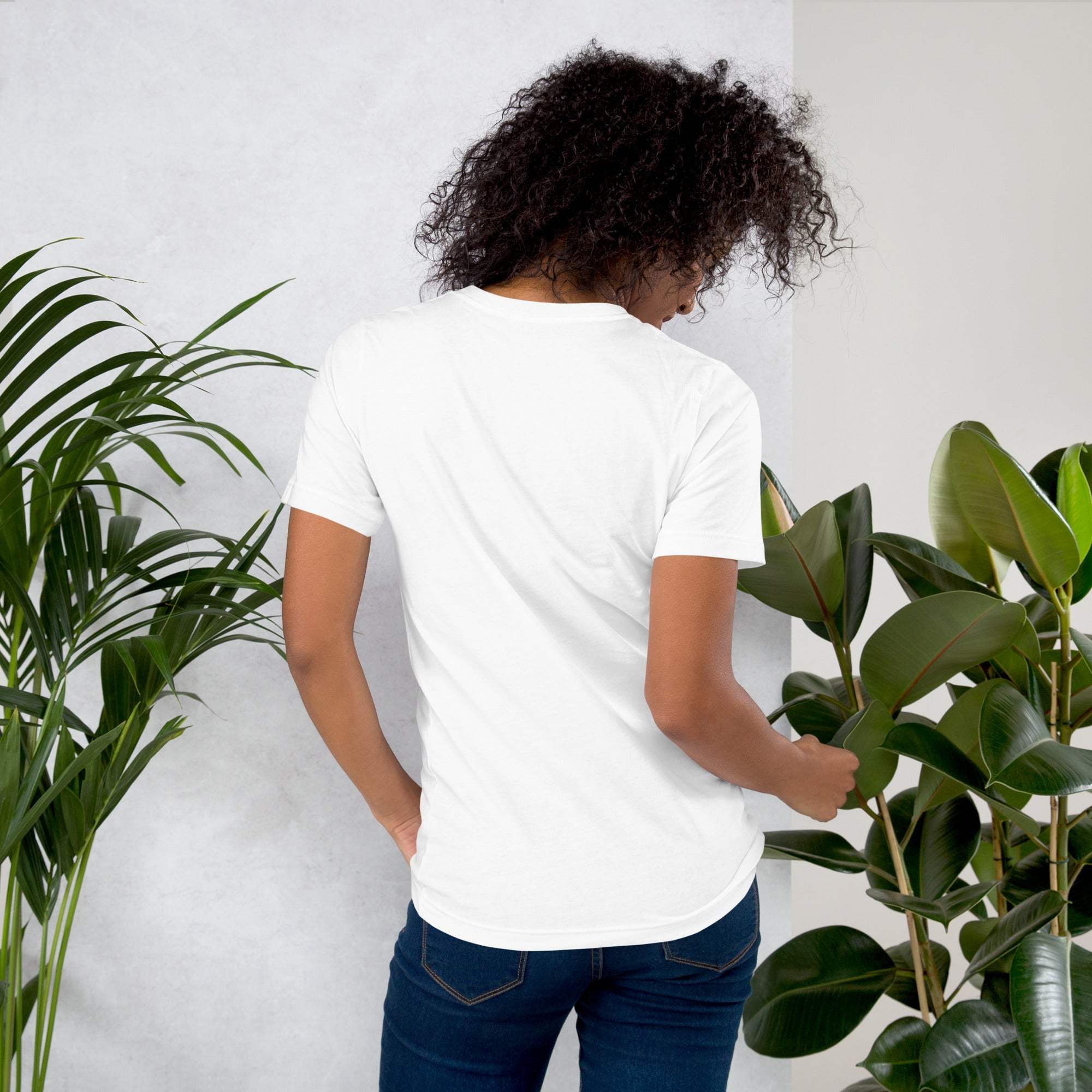 Woman wearing white coffee t-shirt showing back view among green plants