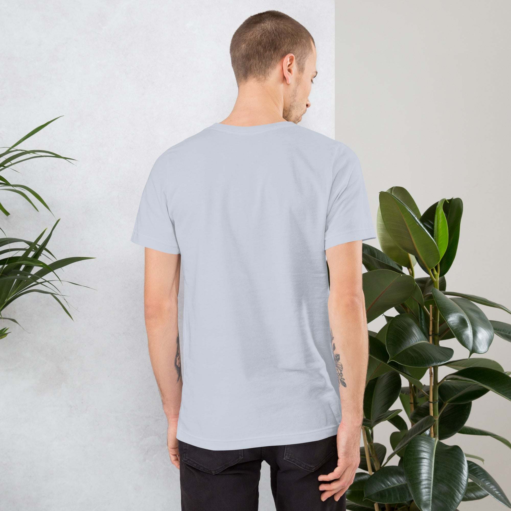Man wearing plain light gray Midwest work ethic t-shirt showing back view standing by green plants
