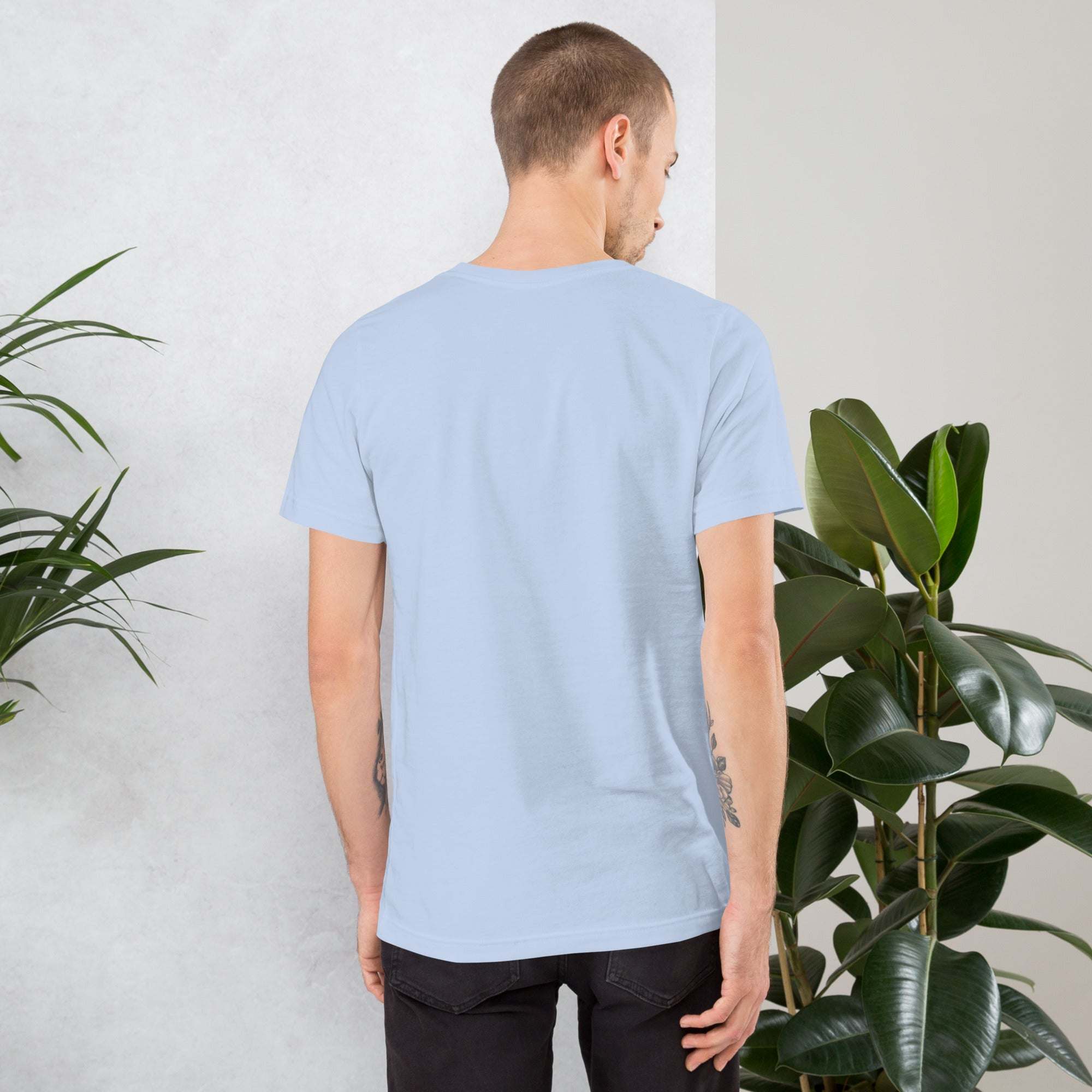 Man wearing light blue Midwest T-Shirt standing near green plants, back view