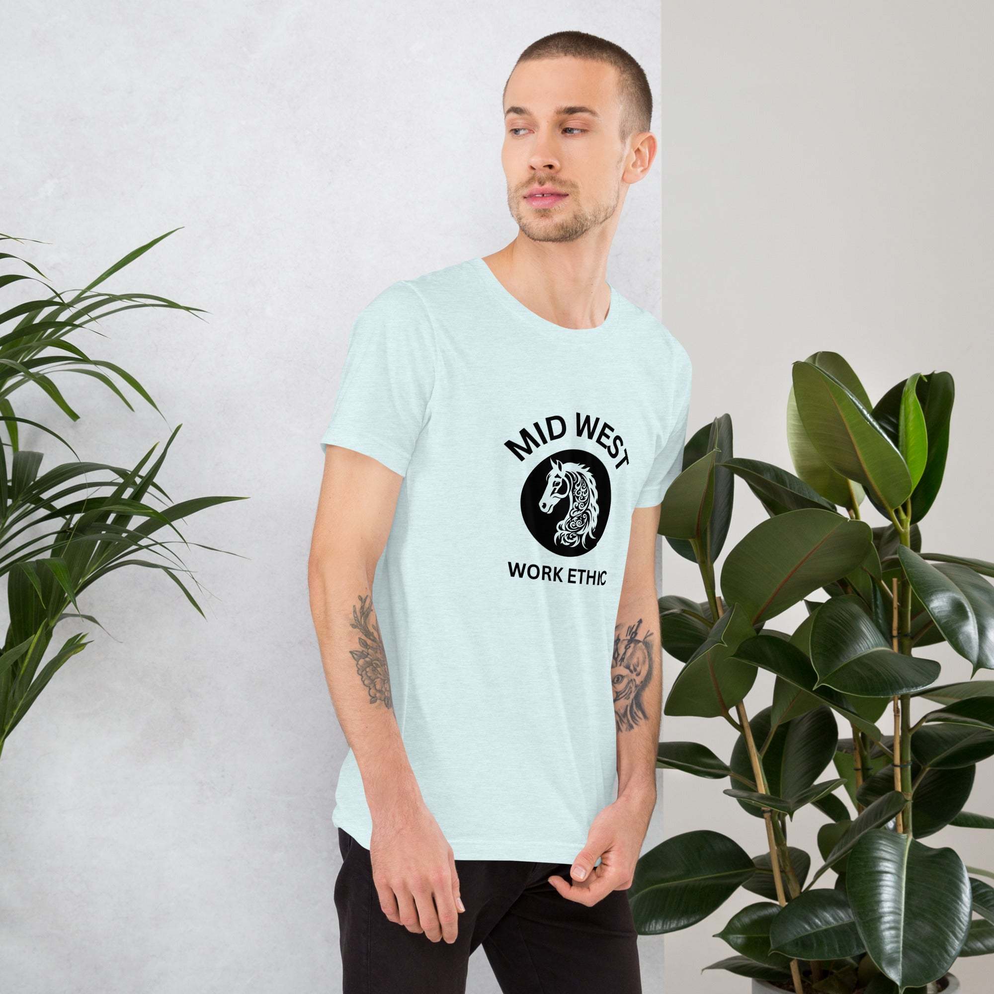 Man wearing Midwest T-Shirt with horse graphic and work ethic text standing near green plants