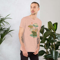 Man wearing vintage aesthetic frog and mushroom graphic t-shirt in soft cotton next to green plants