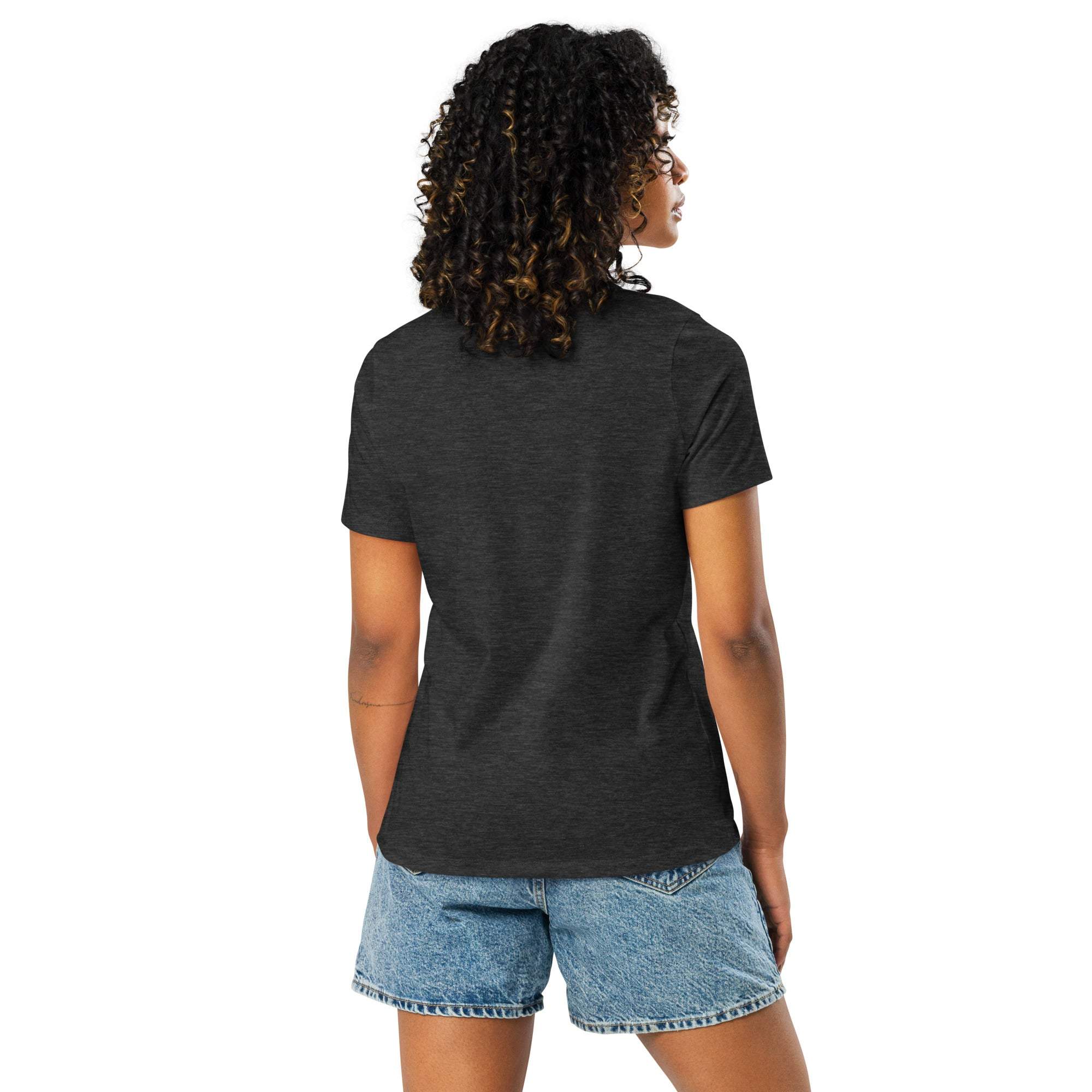 Back view of woman wearing black Adventure Awaits T-Shirt with off-road desert design and denim shorts